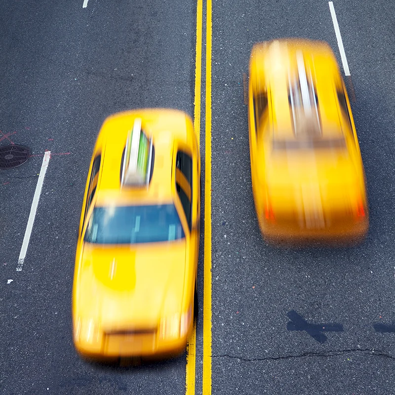 Overhead view of two yellow taxis driving on city street